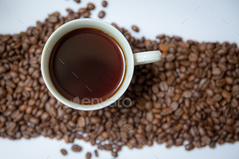 Cup of freshly brewed coffee surrounded by coffee beans
