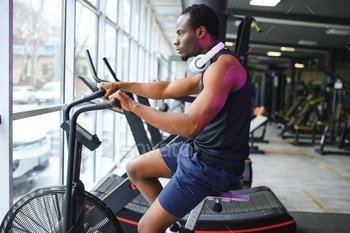 Attractive man at health club, exercising on bike