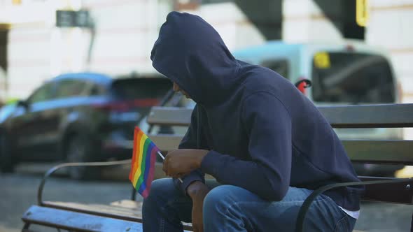 Black Man in Hood Sitting on Bench With Lgbt Minority Flag, Preconceptions