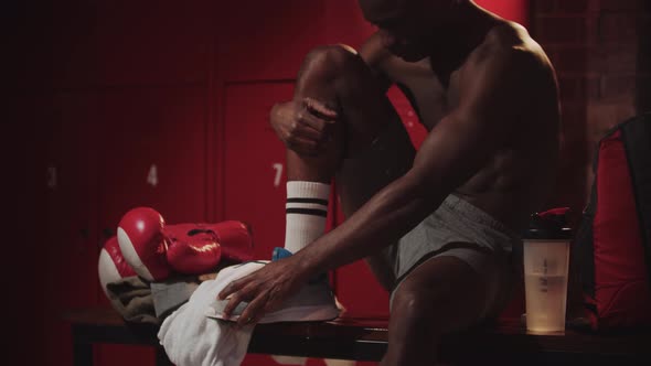 Black Young Man Boxer Tying Up His Sneakers in a Locker Room