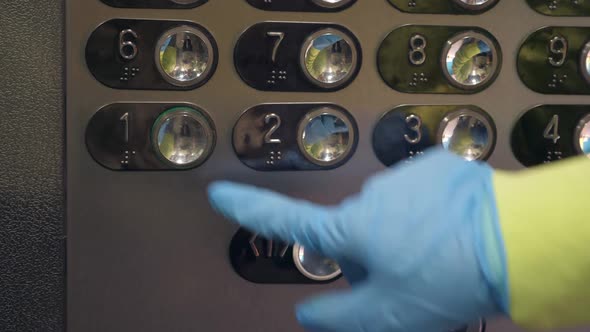 Hand in a Transparent Glove Pushing the Elevator Button. Personal Protection Against Viruses