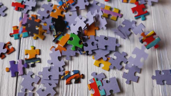 Close-up of colorful puzzle pieces falling on a painted white red wooden floor. Slow motion