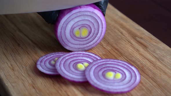 Chef Cuts Fresh Onions with Knife Into Rings on Wooden Cutting Board