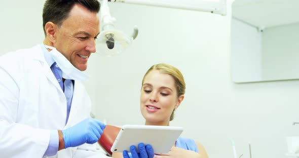 Dentist discussing over digital tablet with female patient