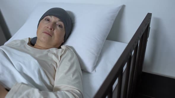 Hopeless Female Patient Suffering Cancer Lying in Sickbed and Looking at Camera