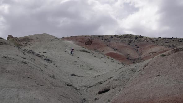 Slow motion of a guy riding mountain bike down hill and hitting jump.