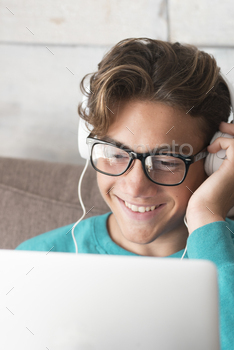 Young and cheerful happy teenager in video conference chat on laptop computer at home