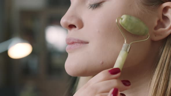 Close Up Of Woman Doing Facial Massage With Roller