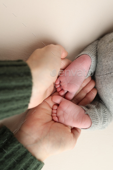 The palms of the father, the mother are holding the foot of the newborn baby.