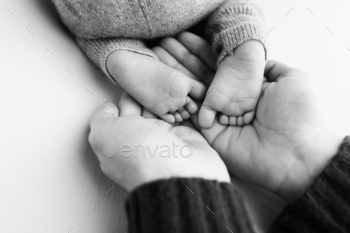 The palms of the father, the mother are holding the foot of the newborn baby.