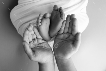 The palms of the father, the mother are holding the foot of the newborn baby.