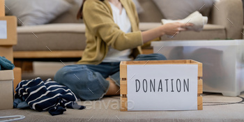 Donation, asian young woman sitting pack object at home, putting on stuff into donate box with