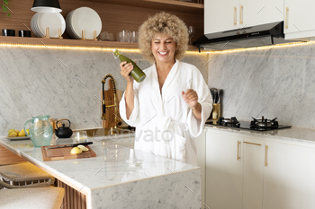 Detox Diet . Woman in Bathrobe Pouring Green Juice in Modern Kitchen