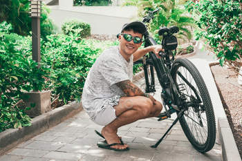 Handsome caucasian active cyclist guy ready use electric bicycle in weekend activity checks his bike