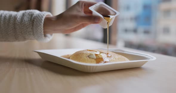 Pouring honey on pancake at coffee shop