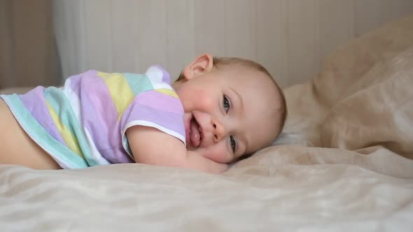 Cute Baby Girl in Striped Shit Lying on Tummy Smiling Laughing and Looking at Camera