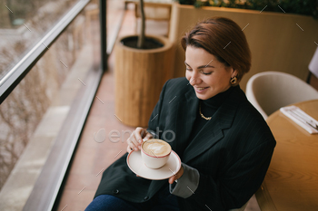 Young woman enjoying coffee in a cozy coffee shop.