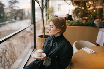 Young woman enjoying coffee in a cozy coffee shop.