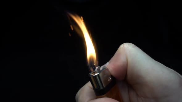 Cigarette Lighter Is Ignited By The Hand On Black Background. Slow Mo