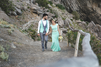 The bride and groom on nature in the mountains near the water. Walk hand in hand.