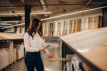 a woman photographs laminate in a hardware store