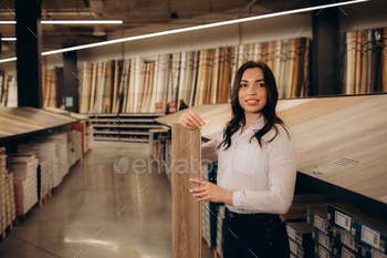 wistful customer stands at showcase with samples of parquet boards.