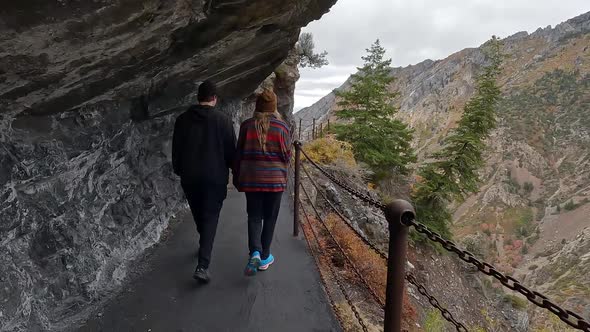 Couple hiking path with guard rail along steep cliff in American Fork Canyon