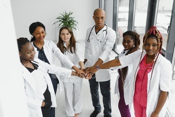Group of doctors putting hands together in clinic. Unity concept.