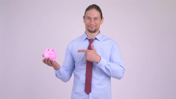 Happy Handsome Businessman Holding Piggy Bank and Giving Thumbs Up