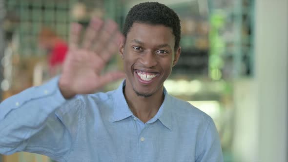 Portrait of Cheerful Young African Man Waving Hello