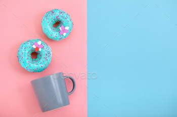 Sweet donuts pink and blue with a mug of coffee. Blue and pink background, game of colors, color