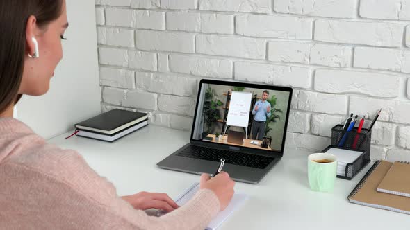 Businesswoman at Home Office Listen Online Video Call Laptop Writes in Notebook