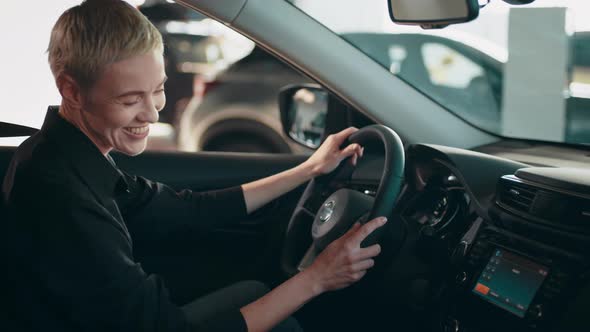 Stylish Girl Sitting in the Car Evaluates the Interior of the Car Inside