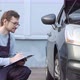 Young auto mechanic checking car wheel in auto service garage. Automobile servicing and repair. - VideoHive Item for Sale