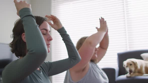 Caucasian lesbian couple keeping fit and meditating on yoga mat