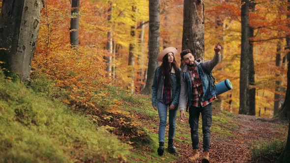 A Young Woman and a Man are Walking Through the Autumn Forest