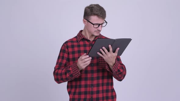 Handsome Bearded Hipster Man Reading Book with Magnifying Glass