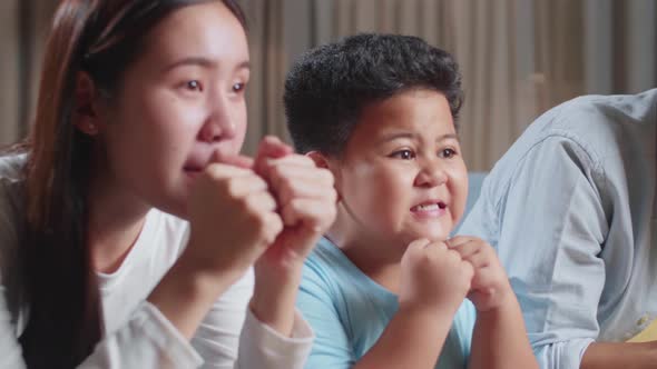 Excited Asian Family Watching Tv Together Sitting On A Sofa In The Living Room At Home