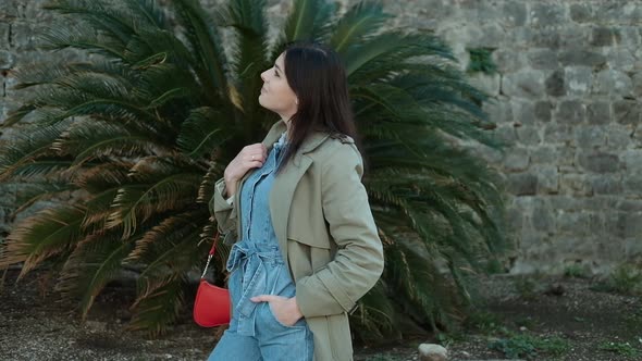 Charming Pretty young woman with brunette hair in denim overalls posing and looking at camera