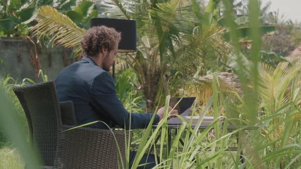 Thoughtful Man Working Under Palm Tree