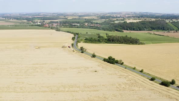 Aerial Drone Shot  a Curvy Road Leads Between Yellow Fields to a Town in a Rural Area