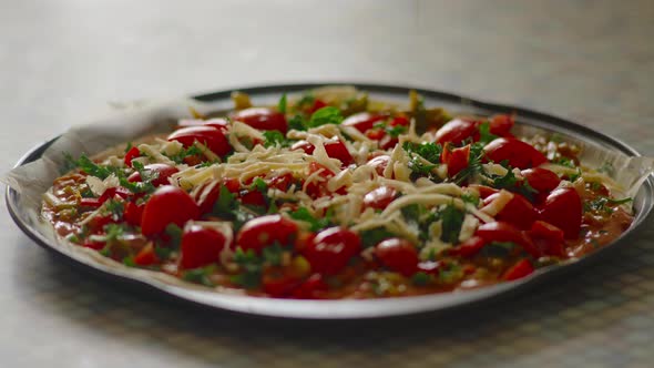 Closeup the Hand of an Elderly Woman Sprinkles Grated Cheese on Pizza Standing on the Kitchen Table