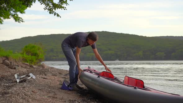 Young Man Inflates His Kayak and Prepares It for Paddling in a Lake or Sea. Slowmotion Shot