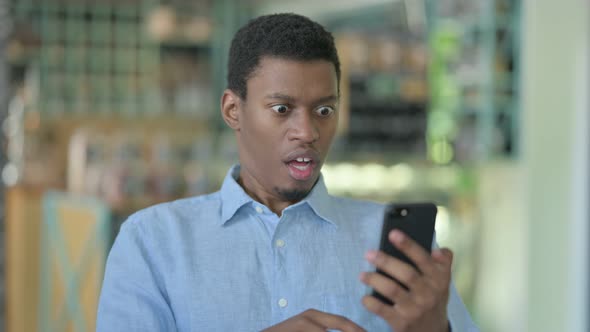 Upset Young African Man Having Loss on Smartphone 