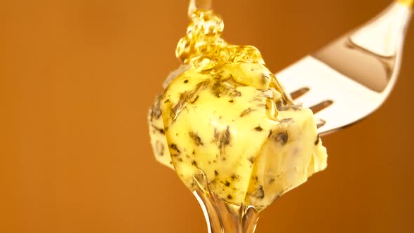 Liquid Organic Honey Dripping on a Fork with Dorbly Cheese on a Light Background