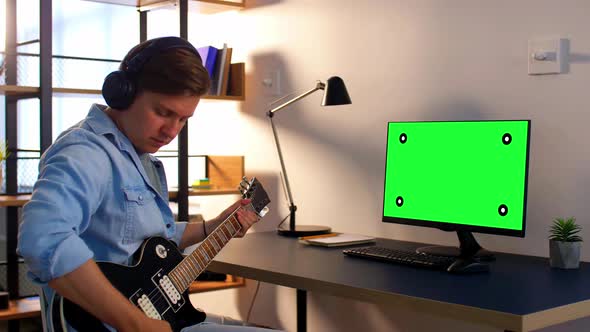 Man in Headphones with Computer Playing Guitar