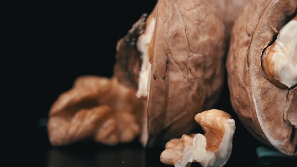 Lot of Walnuts in the Shell are Spinning on a Black Background