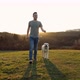 Happy Young Man Walking With His Dog On Meadow At Sunset - VideoHive Item for Sale