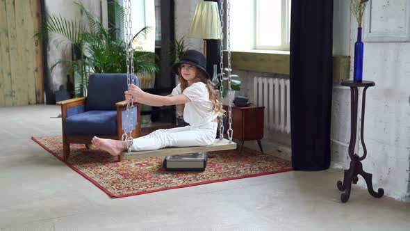 Beautiful Girls Rides in Black Hats on a Swing in the Loft