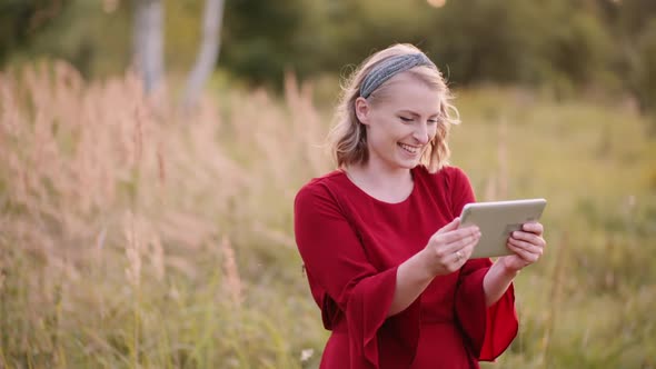 Young Smiling Woman Typing on Digital Tablet Outdoors